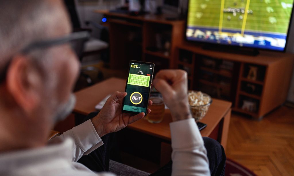 Mature men using smart phone for sports betting.